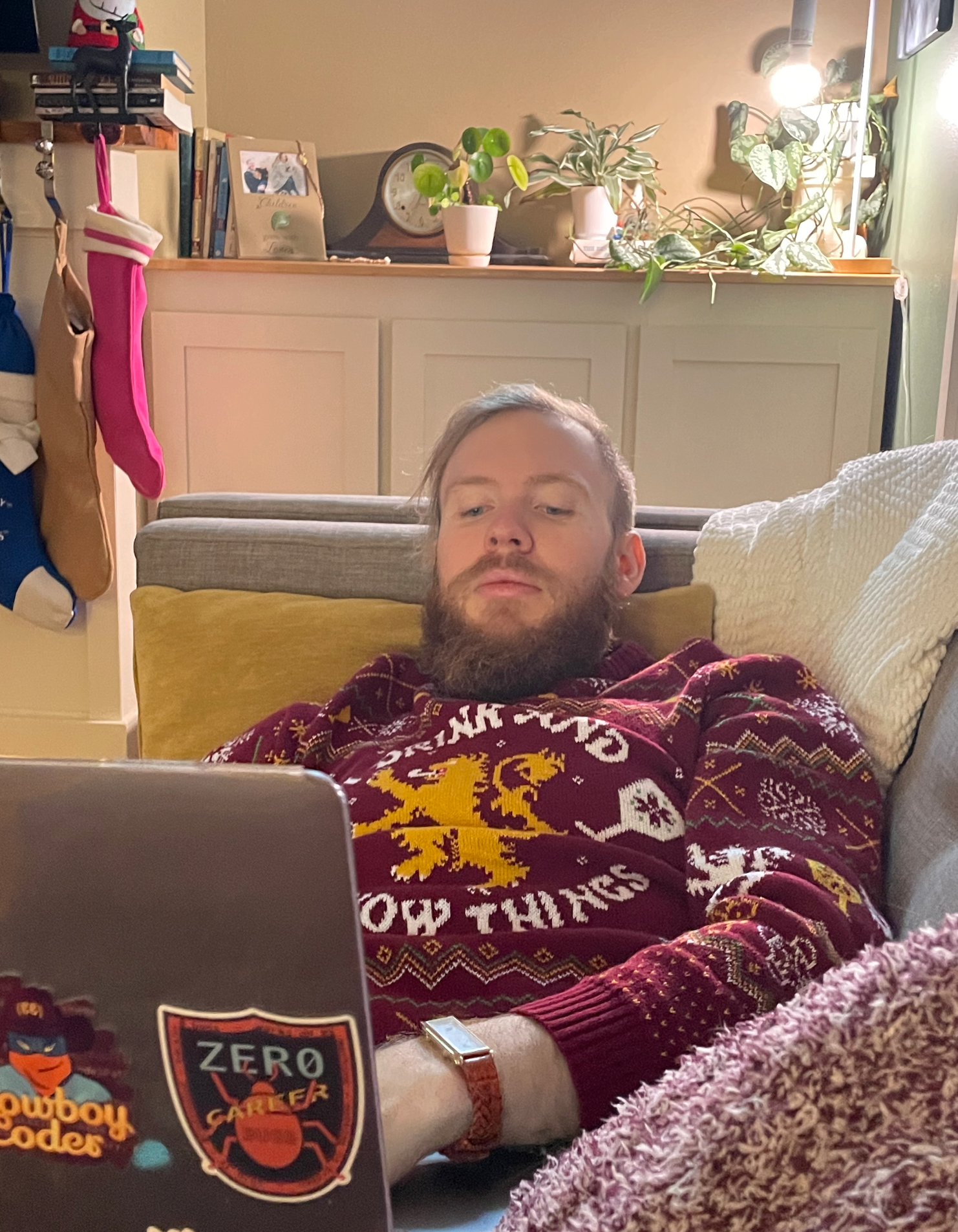The author in a sweater on the couch writing on a laptop.